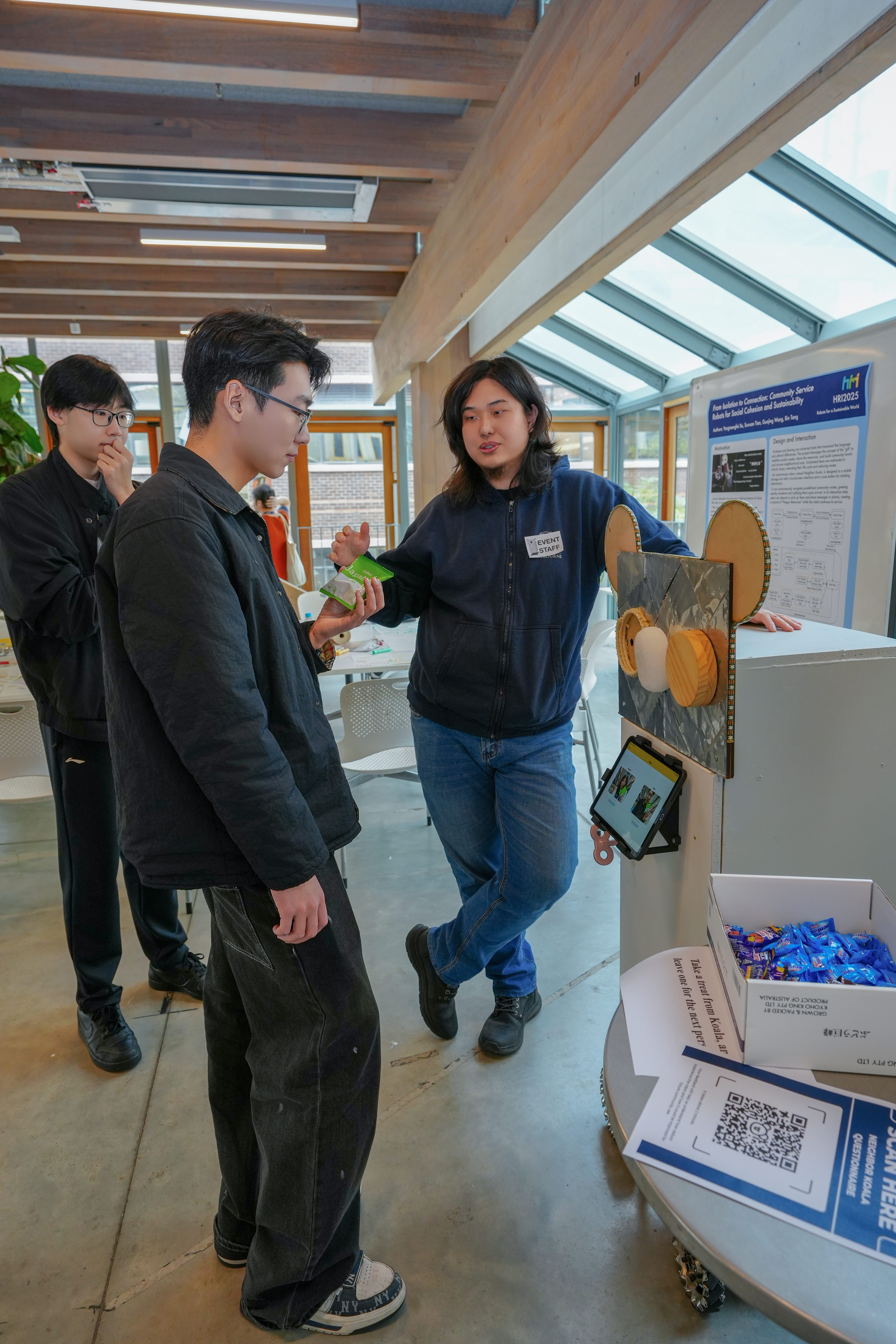 Yangmengfei Xu discussing the Neighbor Koala robot with exhibition visitors